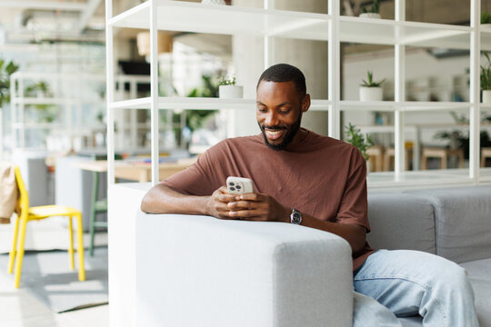 A smiling freelancer reads a message on his smartphone in the office