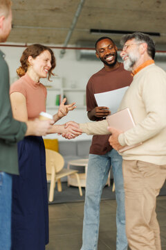 A businesswoman shakes hands with a businessman in the office