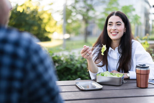 Businesswoman eats healthy salad during outdoor lunch meeting