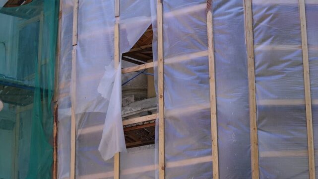 Construction scene features wooden framing with translucent protective sheeting