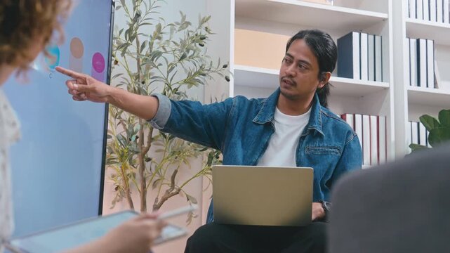 Businessman presenting financial charts to colleagues in modern office meeting.