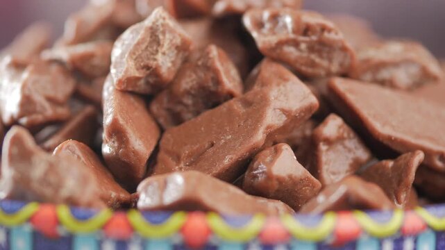 Close up shot of chocolate rocks pieces rotating in colorful bowl