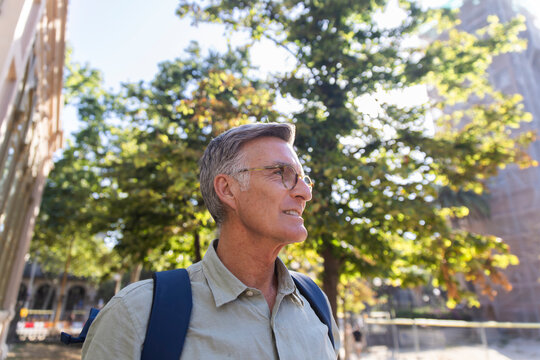 A man wears a backpack in Ciutadella Park at golden hour