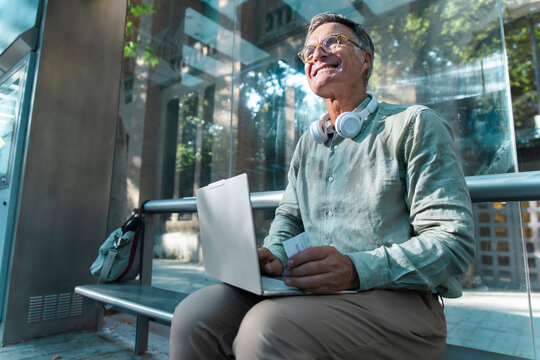 Man works on laptop while waiting at tram station in Barcelona