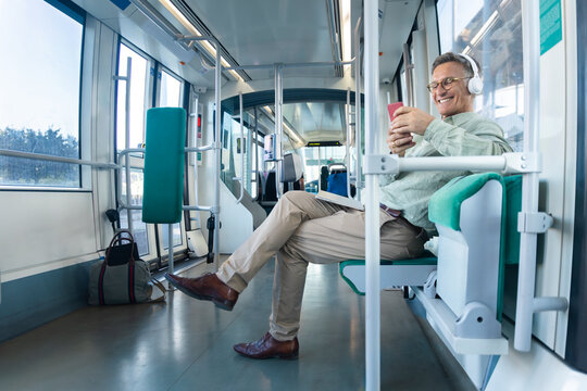 Smiling mature man uses smartphone on a tram indoors