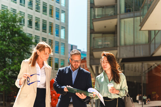 A businessman shows a strategy document to a businesswoman outdoors