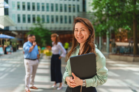 Smiling businesswoman holds a folder outdoors in the city
