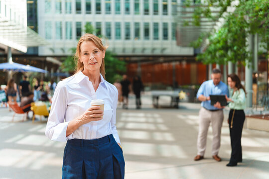 Confident businesswoman holds coffee outside the corporate office