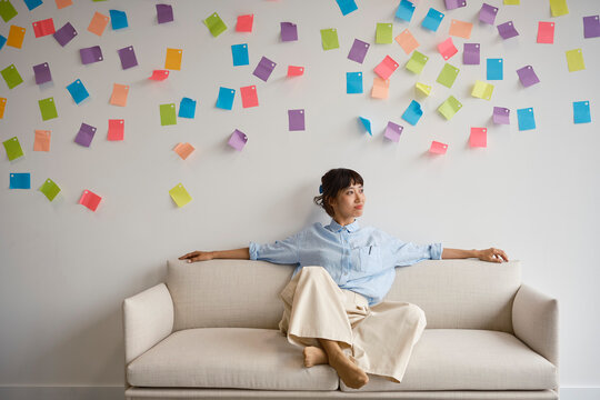 A woman sits on a sofa and contemplates business ideas in an office