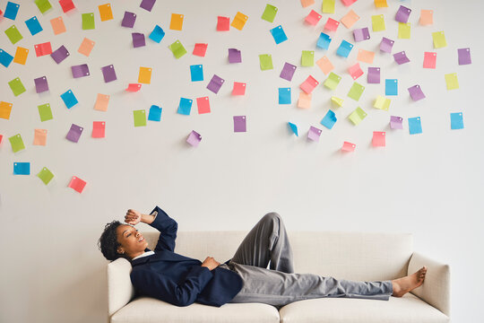Businesswoman rests on a couch under colorful adhesive notes