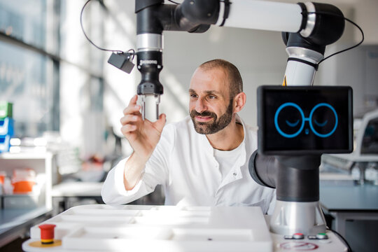 Male engineer tests a robotic arm inside a high-tech laboratory
