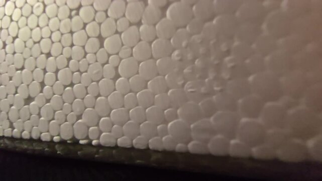 Close-up macro shot of expanded polystyrene (styrofoam) texture showing smooth, interconnected white cellular beads with soft lighting and shallow depth of field. Ideal for abstract backgrounds