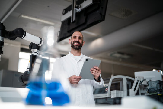 Smiling male scientist holds a tablet in a high tech laboratory