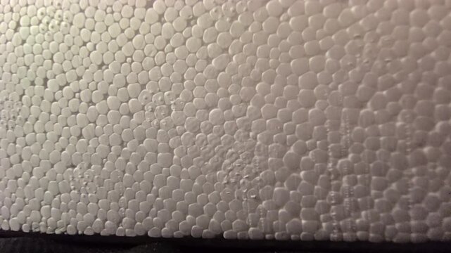 Close-up macro texture of white expanded polystyrene EPS foam beads. Detailed white background pattern of soft foam material, packaging structure, insulated protection surface, and synthetic polymer.