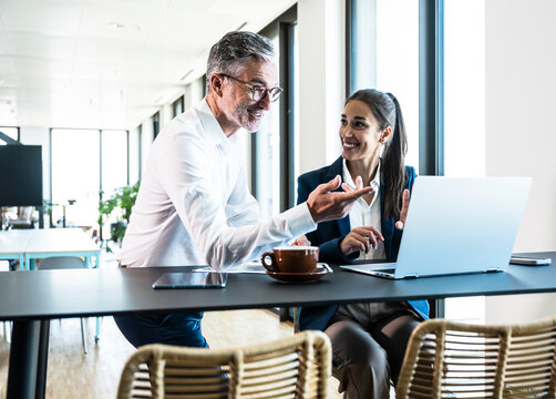 Businessman and businesswoman discuss work on a laptop in the office