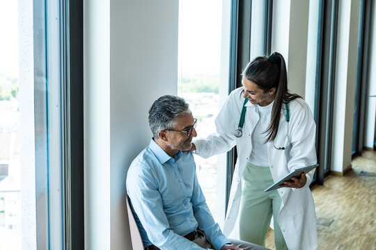 Female doctor advises a male patient with a tablet at the hospital