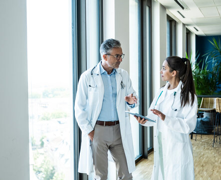 Male and female doctor discuss health advice on a tablet in hospital