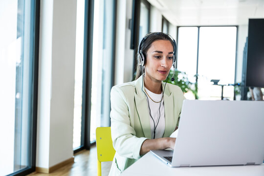 Businesswoman works on a notebook with a headset in the office