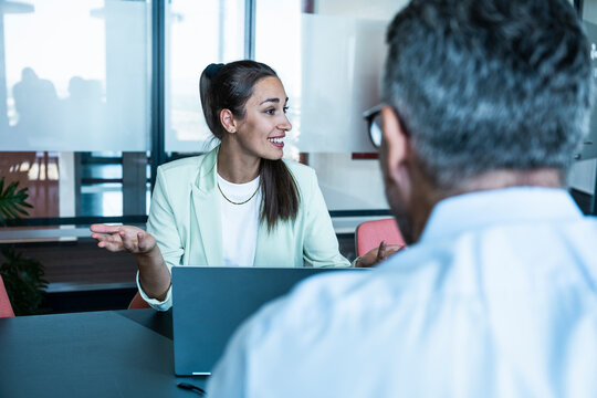 Smiling businesswoman talks to a businessman at the office