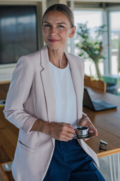Businesswoman holds an espresso cup during a relaxed office break