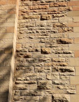 Chiseled sandstone masonry wall texture with warm natural sunlight and shadow