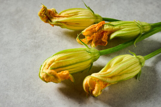 Fresh squash blossoms on a grey surface ready for cooking