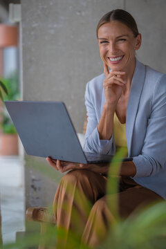 Confident businesswoman works on laptop outdoors