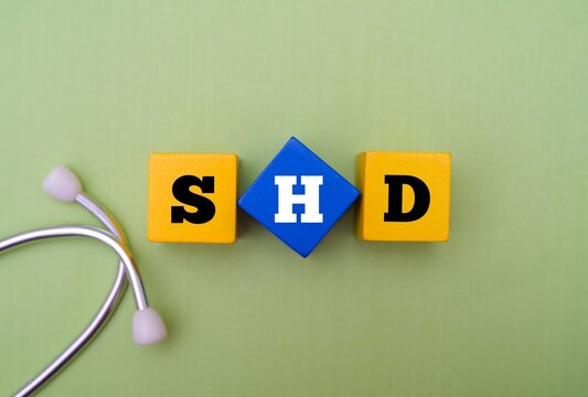 Healthcare and medical concept with text SHD. SHD acronym for "STRUCTURAL HEART DISEASE" with a stethoscope on green background