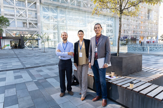 A business team stands smiling at an urban plaza