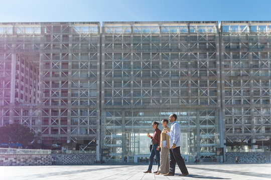 Business colleagues walk and talk outside a modern corporate building