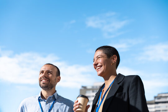 Smiling businessman and businesswoman enjoy a coffee break outdoors