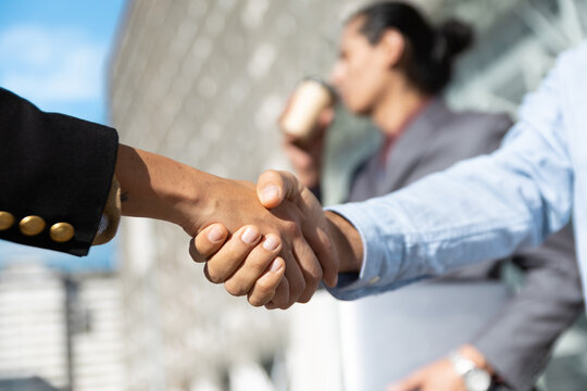 A businesswoman shakes hands with a businessman outdoors