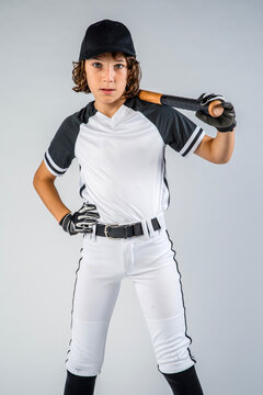 Youth baseball player in uniform standing with bat on shoulder and hand on hip, three-quarter body shot