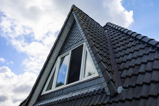 Building roof with dormer window under a blue sky