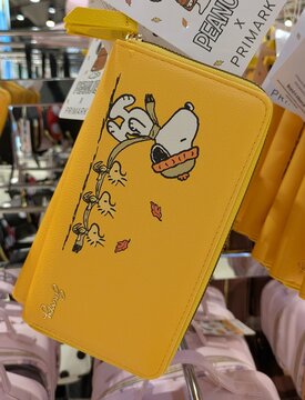 Tiempo de oto&ntilde;o. Bolso pouch con cremallera con Snoopy con gorro de lana compartiendo bufanda con Woodstock y dos p&aacute;jaros, mientras caen hojas de &aacute;rbol. Primark, Madrid, Espa&ntilde;a, 31 de julio de 2026