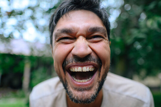 A happy man laughs out loud outdoors during summer