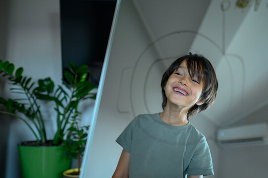A smiling boy looks at his astronaut reflection in the mirror