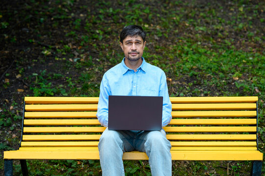 Businessman works on a laptop on a park bench
