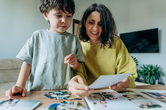 Smiling mother and son look at a family photo at home