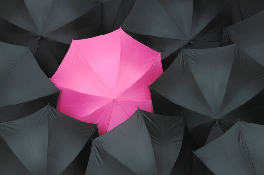 Open black umbrellas with one pink umbrella, close up