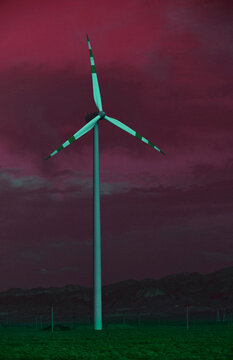 Surreal magenta sky over a wind turbine in a green landscape