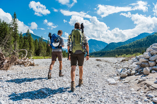 Germany, Bavaria, back view of two hikers walking in dry creek bed