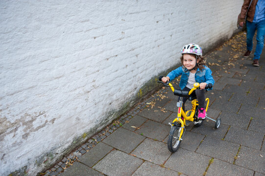 Daughter riding bicycle with training wheels