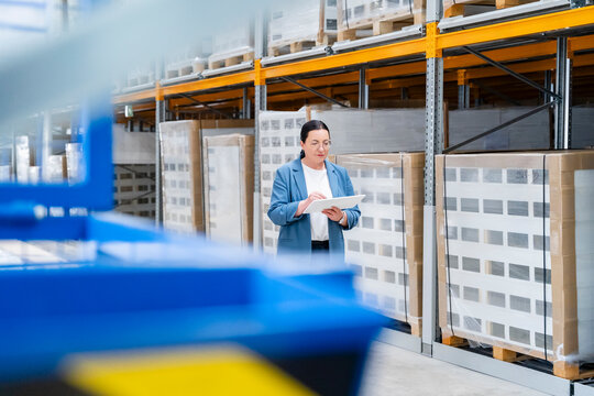 Female manager checks inventory on a tablet in a large warehouse