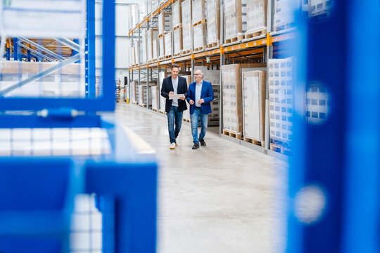 A manager and a supervisor discuss inventory in a warehouse