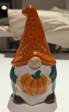 Tiempo de oto&ntilde;o Vista de cerca de un decorativo gnomo de cer&aacute;mica, con un enorme sombrero naranja, sujetando una calabaza, en el estante de una tienda
