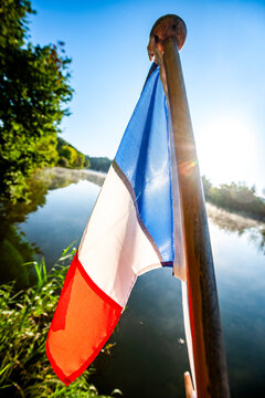 French flag waves on an electric boat stern on the Saone river