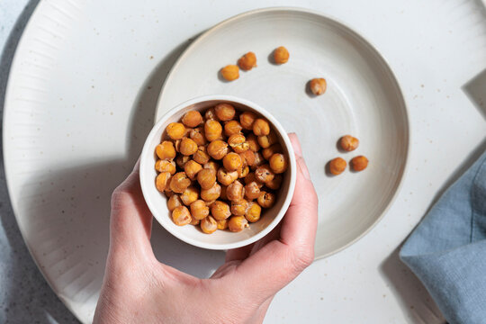 Woman holds a bowl of healthy homemade roasted chickpeas indoors