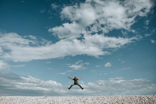 A happy woman celebrates freedom by jumping under a blue sky
