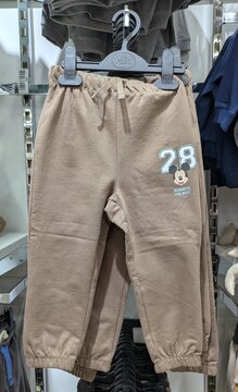 Tiempo de oto&ntilde;o. Pantal&oacute;n deportivo con estampado de la cabeza de Mickey Mouse de Disney y el texto 28 Always the Best, en tienda de ropa de Madrid, Espa&ntilde;a, 18 de agosto de 2026